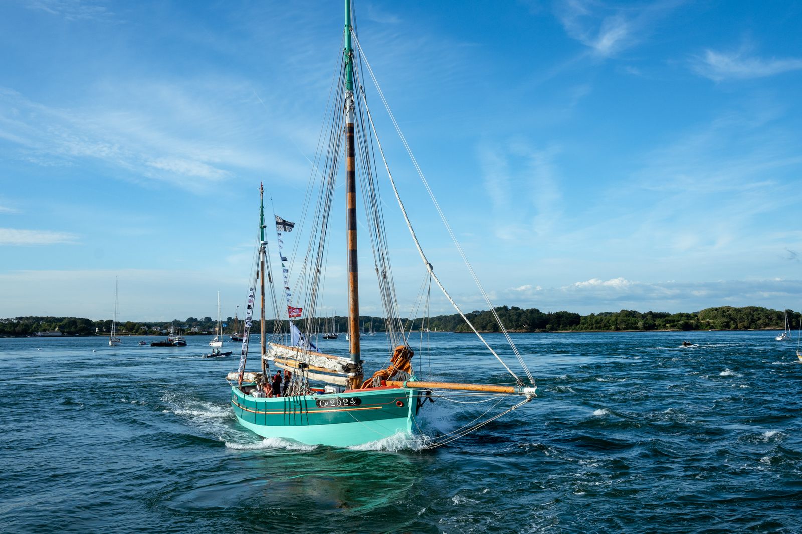 Un voilier traditionnel naviguant dans les eaux pittoresques de Bretagne sous un ciel bleu clair.